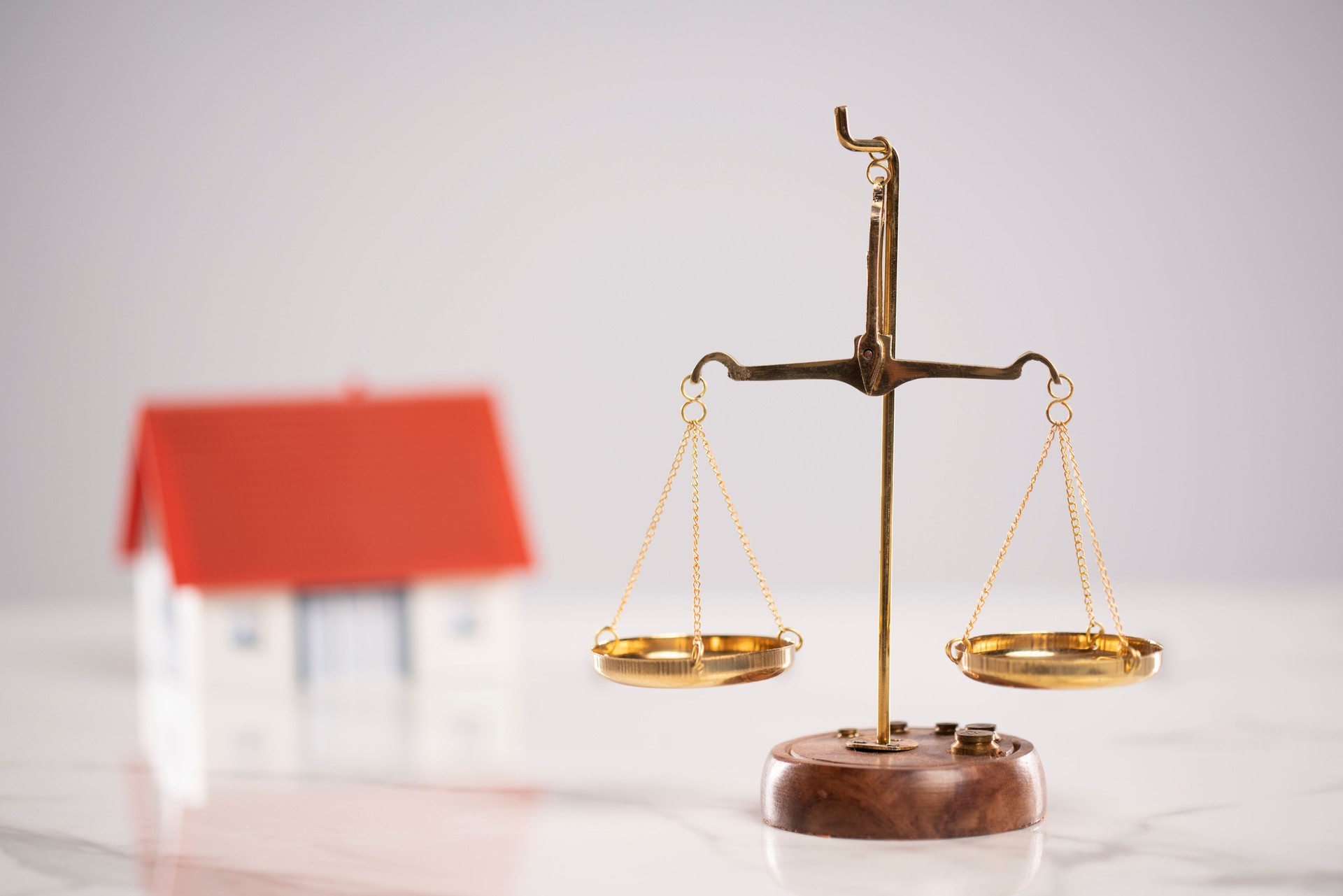 Scales of justice and a model house are on the white table
